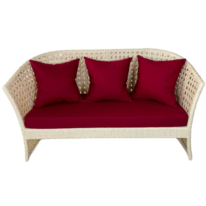 Wicker loveseat with red cushions on a white background